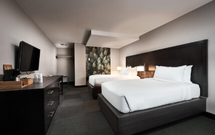 Spacious hotel room with two queen beds and Tofino Resort + Marina forest photography piece