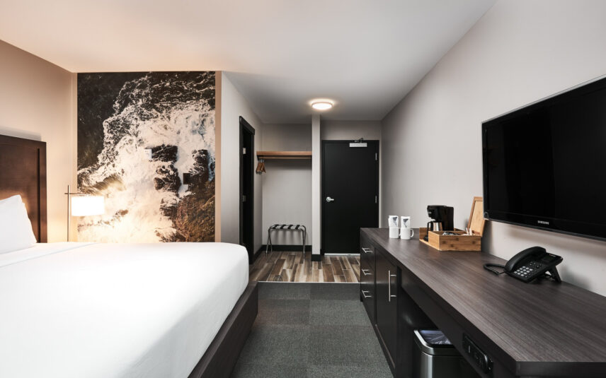 King bed in cozy room with ocean-inspired artwork above the headboard