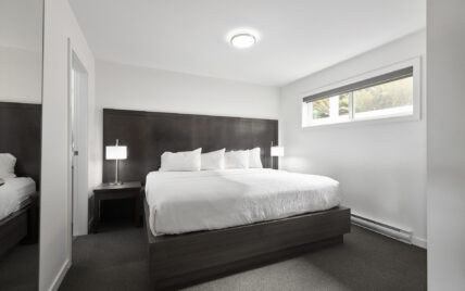 King bed with soft linens and forest-inspired wall art