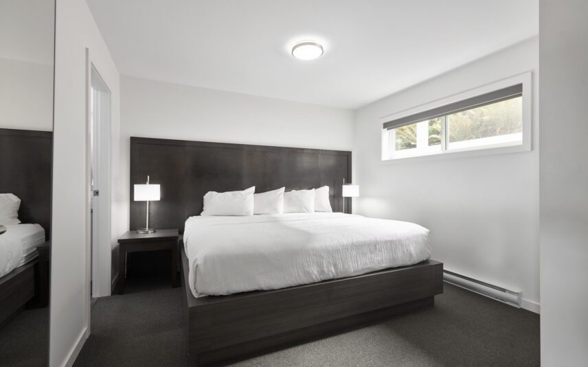 King bed with soft linens and forest-inspired wall art