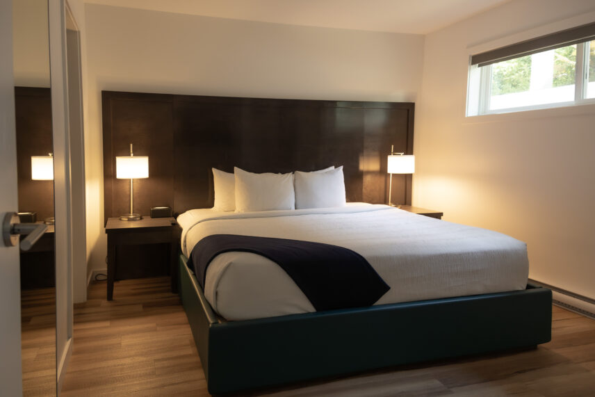 King bed with soft linens and forest-inspired wall art