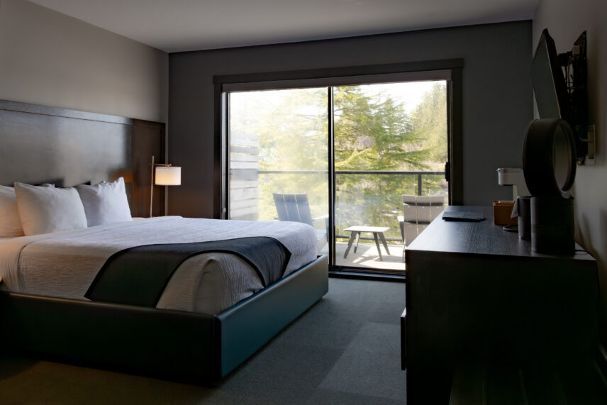 King bed facing the lush green landscape through wide windows