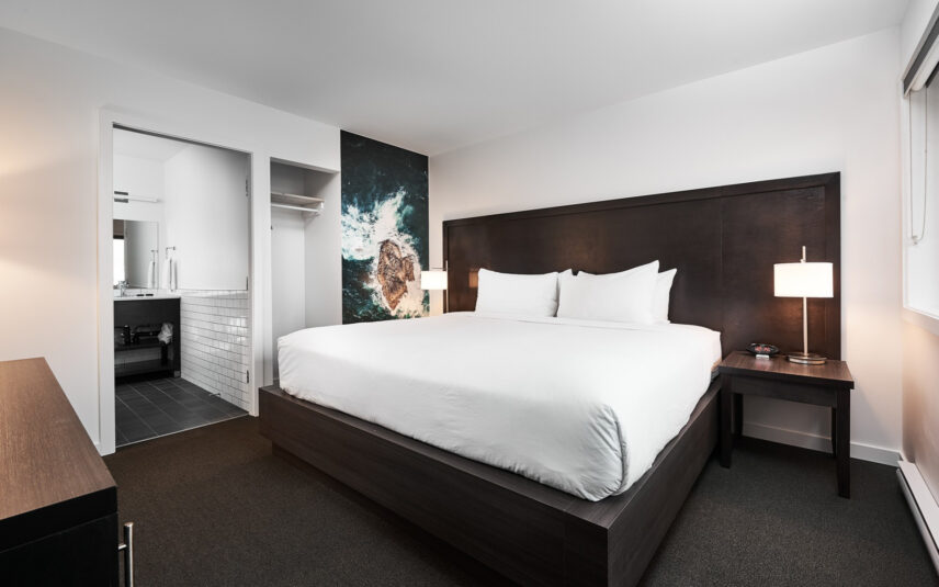 Queen bed with crisp white linens and ocean wave photography