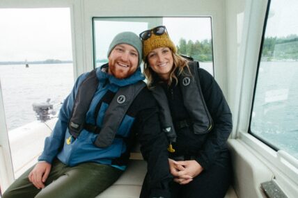A smiling couple enjoys the ocean breeze while cruising on a fishing boat