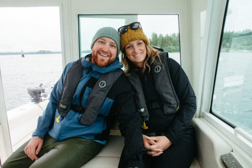 A smiling couple enjoys the ocean breeze while cruising on a fishing boat