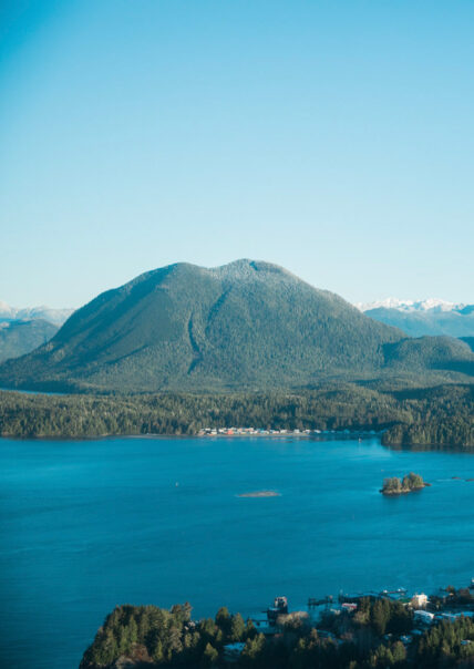 Mountain landscape representing Tla-o-qui-aht First Nation territory with cultural emblem