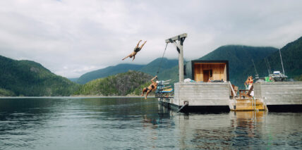 Group of guys jumping off a rope swing into the water at the floating sauna in Tofino