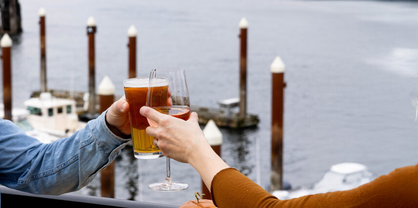 Guests toasting with beer and wine glasses overlooking the Tofino harbour at sunset