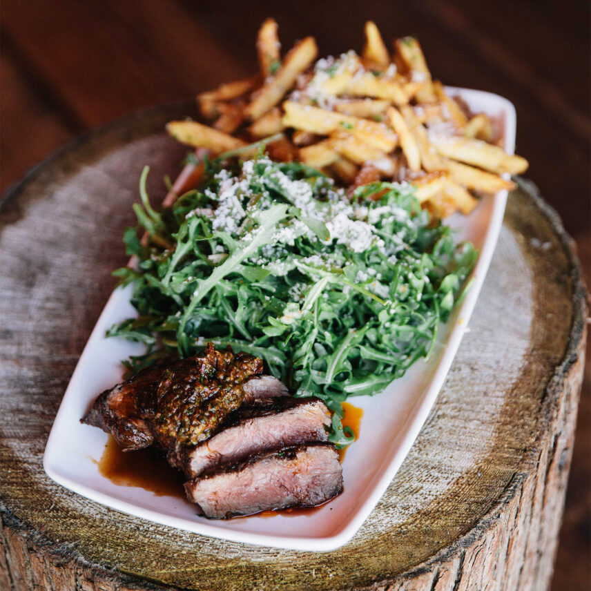 A plated steak salad with golden fries on the side