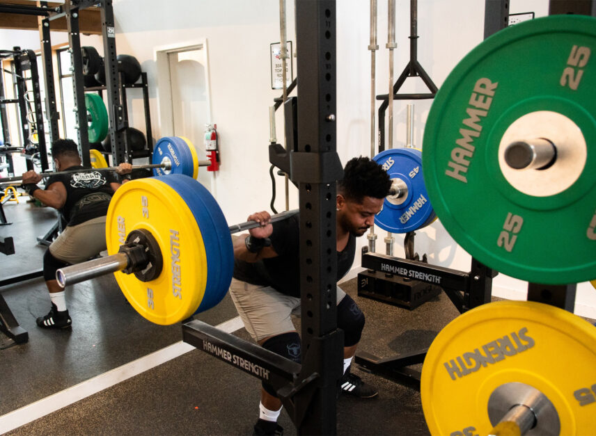 Man doing squats at a squat rack inside the gym