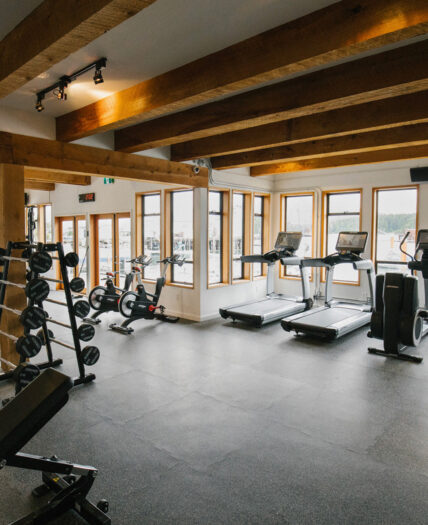 Modern gym with cardio machines and free weights overlooking Tofino harbour