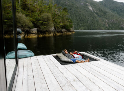 Couple lounging in a hammock with breathtaking views of Tofino’s inlet from the floating sauna
