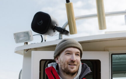 Captain Dave wearing a toque and smiling on board a boat