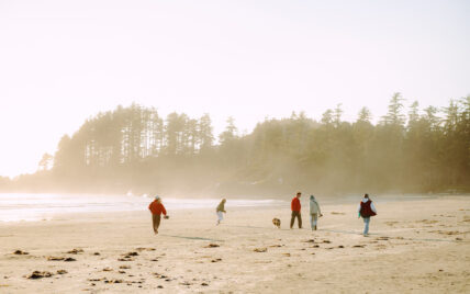 People running along the beach in Tofino during a sunny, foggy summer morning