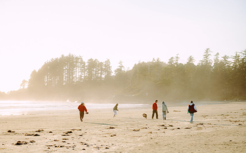 People running along the beach in Tofino during a sunny, foggy summer morning