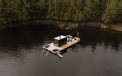 Aerial view of Tofino’s remote floating sauna with guests diving into the ocean from the dock