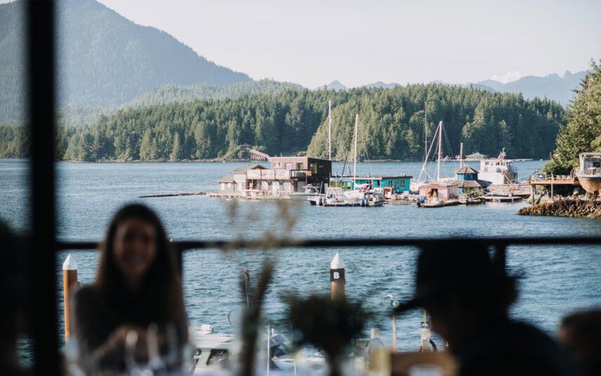Silhouettes of people dining with a view of the harbour and mountains at sunset