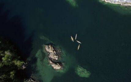 Aerial view of colorful kayaks floating in Clayoquot Sound near rocky islands