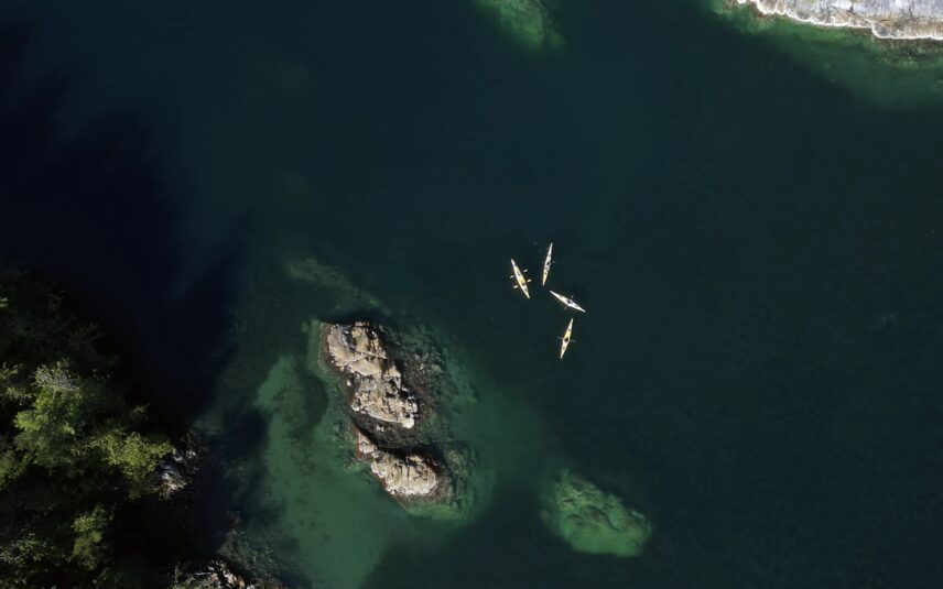 Aerial view of colorful kayaks floating in Clayoquot Sound near rocky islands