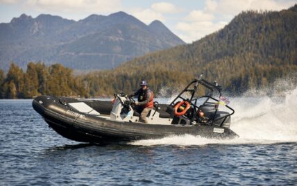 Man confidently captains a boat, creating a dynamic wake on Clayoquot Sound