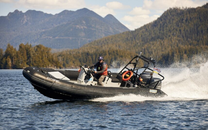 Man confidently captains a boat, creating a dynamic wake on Clayoquot Sound