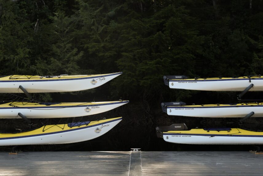 Brightly coloured yellow sea kayaks lined up on the dock, ready for a Tofino paddling adventure