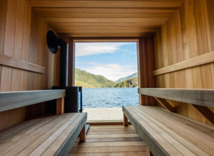 Inside the floating sauna with wooden benches and panoramic views of Tofino’s inlet and mountains
