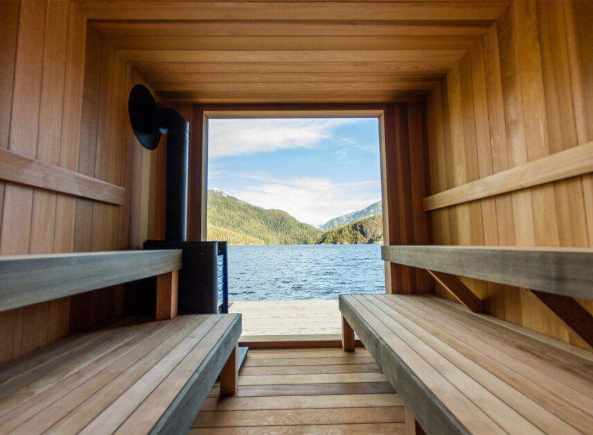 Inside the floating sauna with wooden benches and panoramic views of Tofino’s inlet and mountains