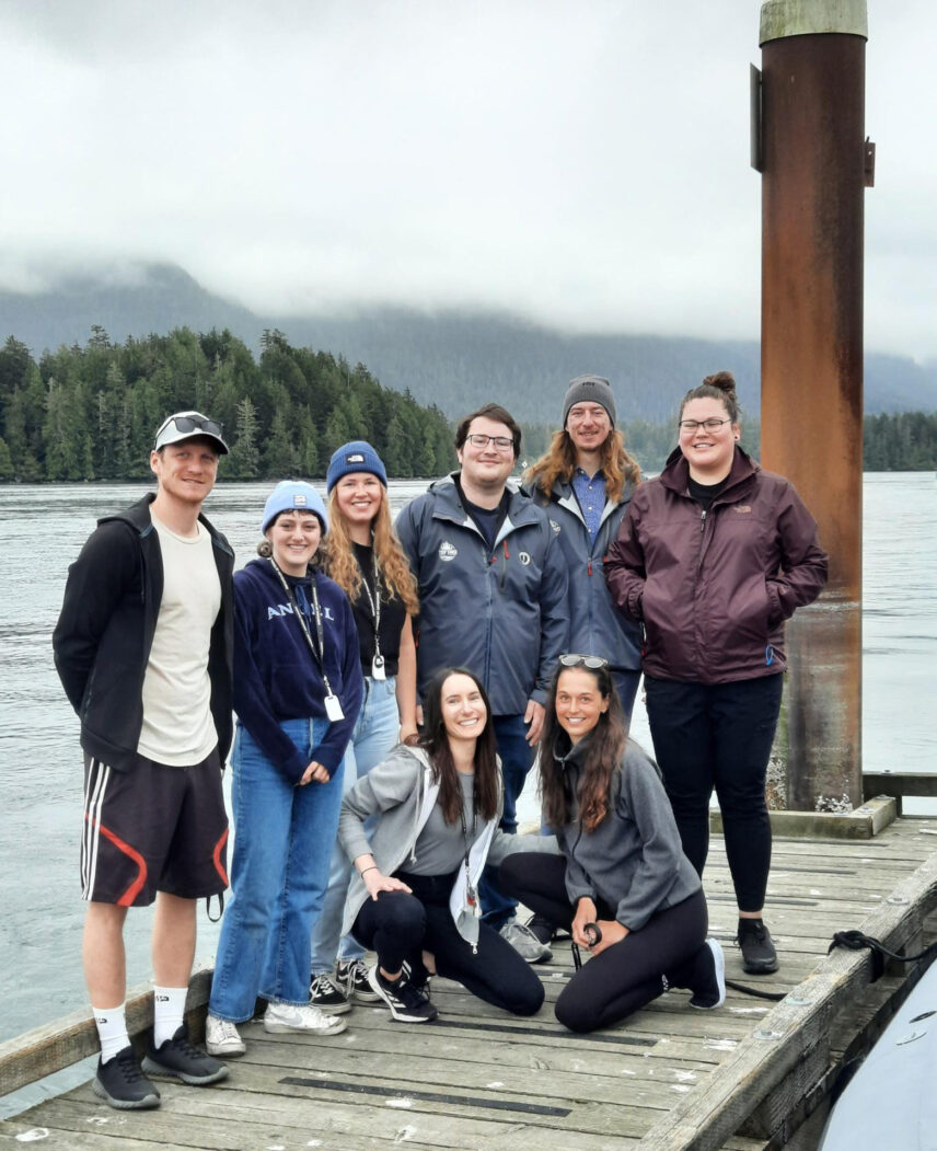 Smiling Tofino Resort + Marina team standing on the dock with marina views
