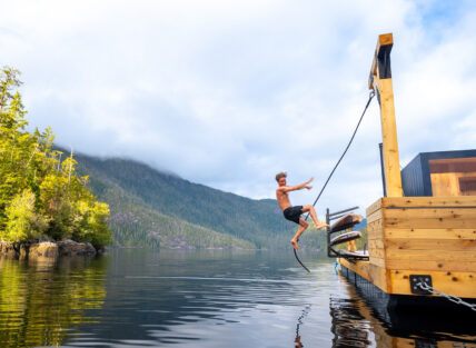 Person leaping off a rope swing at the floating sauna near Tofino
