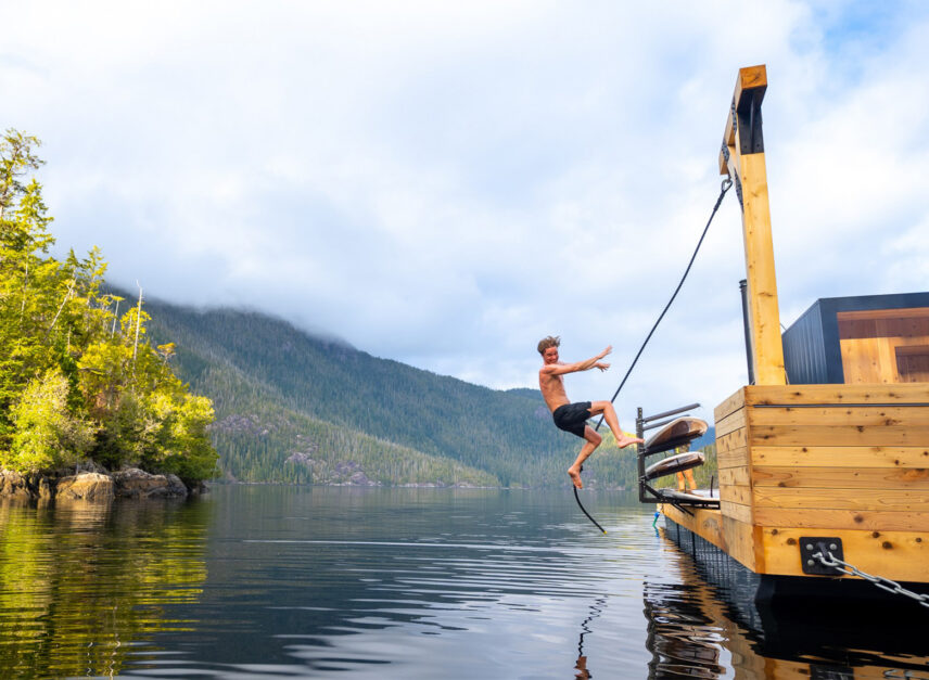 Person leaping off a rope swing at the floating sauna near Tofino