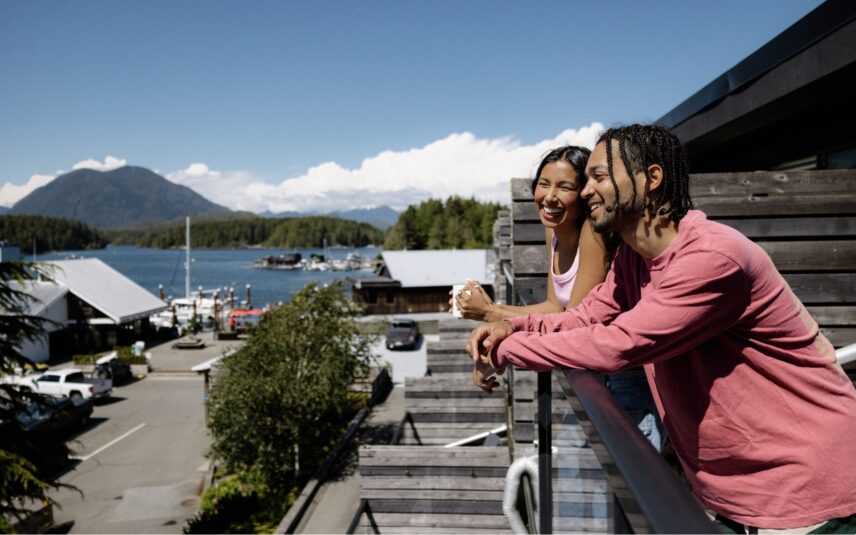 Couple smiling on a private balcony overlooking Clayoquot Sound at Tofino Resort + Marina