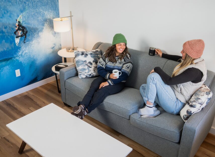 two friends sitting on a couch in a room and chatting