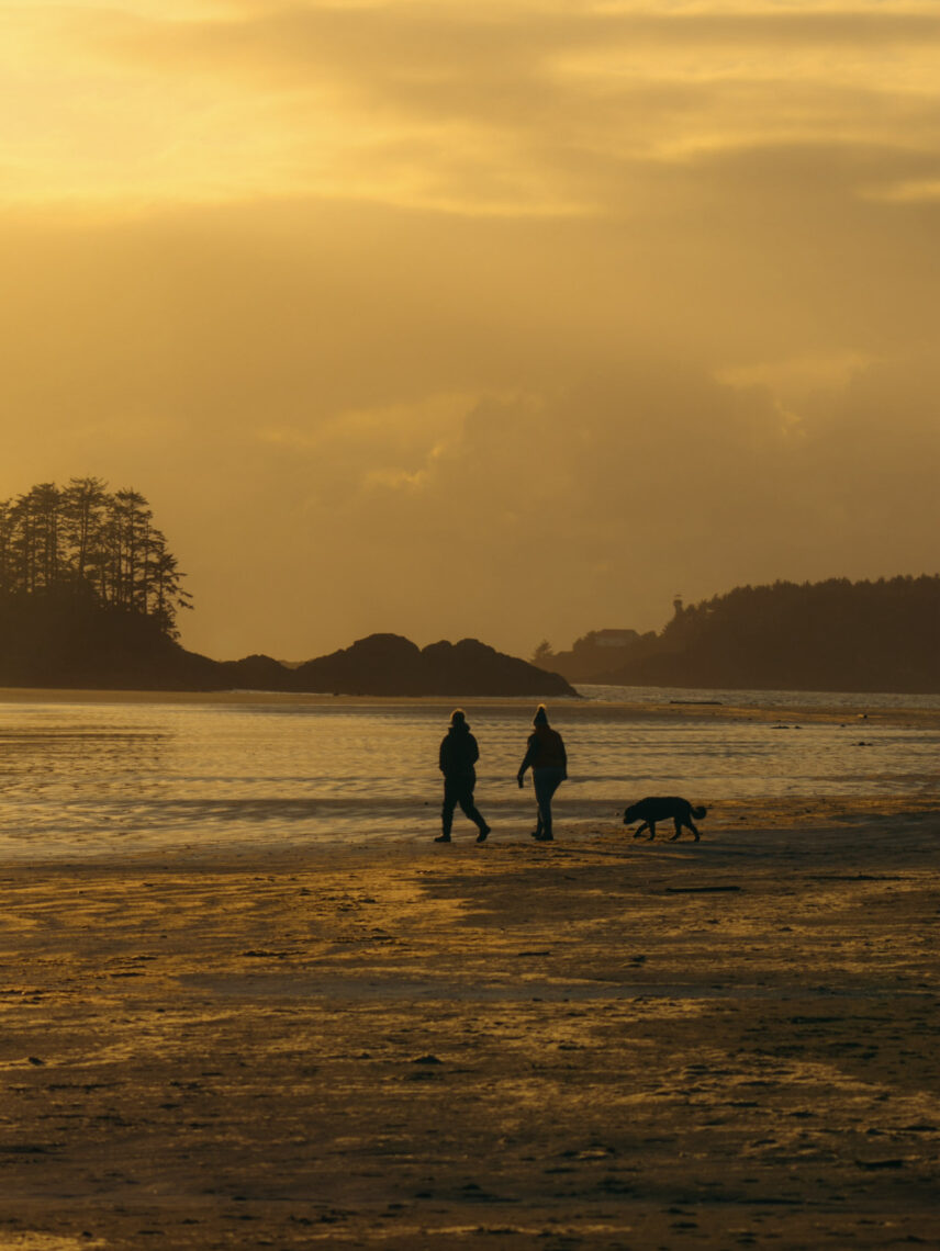 couple and dog walking on a Tofino beach